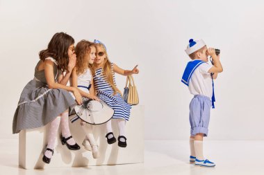 Gri arka planda poz veren çocukların portresi. Dürbünle bakan çocuk, konuşan kızlar. Toplantı. Çocukluk kavramı, arkadaşlık, eğlence, yaşam tarzı, moda, eski tarz, duygular