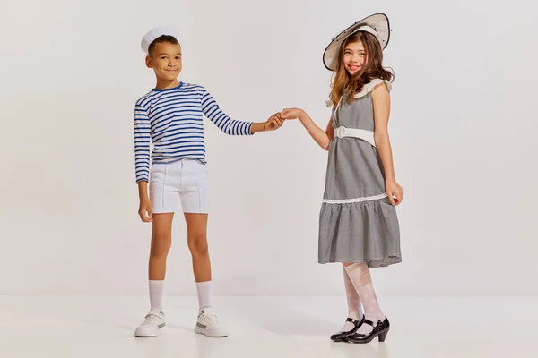 子供の肖像画 縞模様のベストの少年とグレーの背景にポーズをとってエレガントなドレスの10代の女の子 友達だ 子供時代 楽しさ ライフスタイル ファッション レトロスタイル 感情の概念 — ストック写真