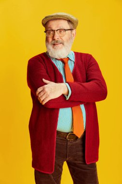 Klasik elbiseli ve gözlüklü son sınıf öğrencisinin portresi parlak sarı arka planda poz veriyor. Sakin görünüyor. Duyguların kavramı, yüz ifadesi, yaşam tarzı, modern moda, tarz