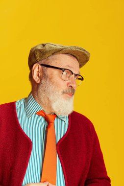 Klasik kıyafetler, gözlükler ve parlak sarı arka planda poz veren son sınıf öğrencisinin portresi. Hoş bir görünüş. Duyguların kavramı, yüz ifadesi, yaşam tarzı, modern moda, tarz