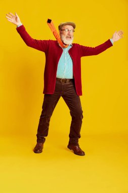 Klasik kıyafetler, gözlükler ve parlak sarı arka planda poz veren son sınıf öğrencisinin portresi. Heyecan duyguları. Duyguların kavramı, yüz ifadesi, yaşam tarzı, modern moda.