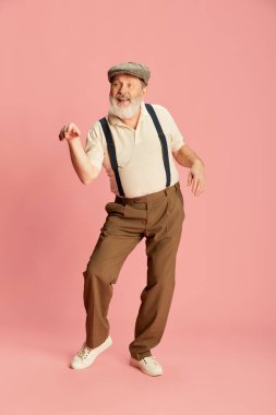 Klasik giyinmiş, pembe arka planda dans eden son sınıf öğrencisinin portresi. Neşeli, neşeli. Duyguların kavramı, yüz ifadesi, yaşam tarzı, modern moda, tarz