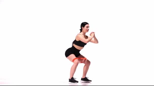 Junges Sportliches Mädchentraining Mit Fitness Gummibändern Vor Weißem Studiohintergrund Kniebeugen — Stockvideo