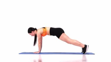 Genç, sportif kız, beyaz stüdyo geçmişi üzerinden antrenman yapıyor. Tahtada duruyor ve elini kaldırıyor. Denge. Modern spor, aksiyon, hareket, gençlik konsepti. Fitness, hobi, sağlıklı yaşam tarzı