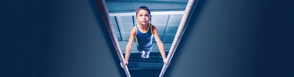 Image of little boy, child training, doing gymnastics exercises on parallel bars at gym. Developing strength and endurance. Concept of sportive lifestyle, childhood, health. Banner, flyer