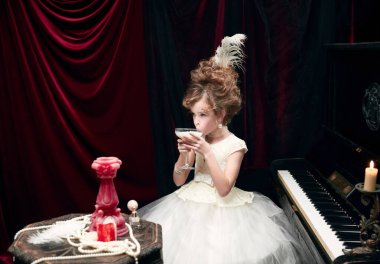 Şirin küçük bir kız, ortaçağ kraliyet ailesinden birinin resmi piyanonun başında oturmuş milkshake içiyor. Tarihi yeniden yapılanma, çağların karşılaştırılması, ortaçağ modası, duygular, çocukluk.