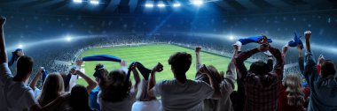 Futbolun arka görüntüsü, futbol taraftarlarının takımına tezahürat yapması, akşam vakti kalabalık stadyumda bayrak tutması. Duygu patlaması. Spor, kupa, dünya, takım, etkinlik, rekabet, hobi kavramı