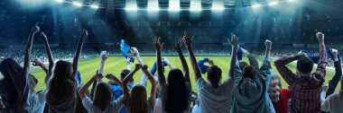 Futbolun arka görüntüsü, futbol taraftarları akşam vakti kalabalık stadyumda duygusal olarak takımlarını alkışlıyorlar. Çeşitli gruplar. Spor, kupa, dünya, takım, etkinlik, rekabet, hobi, yaşam tarzı kavramı