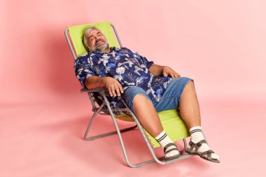 Pembe stüdyo arka planında duran şık gömlekli olgun bir adamın portresi. Rahatlama, tatil. Keyif. Amerikan tarzı kavramı, kültür, duygular, yüz ifadesi, yaşam tarzı