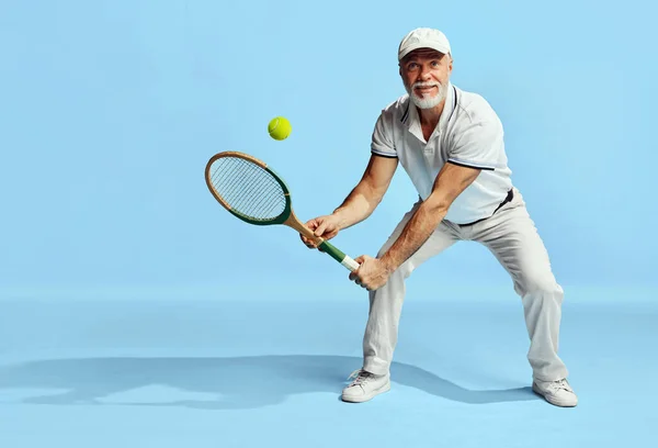积极的退休生活 穿着时髦的白色服装 穿着蓝色背景网球的英俊老年男子的画像 休闲活动 业余爱好 生活方式 复古风格的概念 — 图库照片