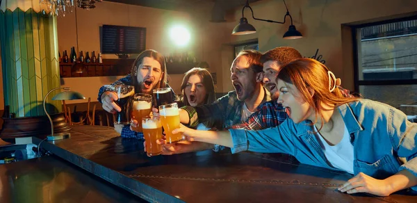一群年轻人 男人和女人在酒吧里碰碰啤酒杯 看比赛 粉丝们在感情上鼓舞着最喜爱的运动队 进球了比赛 锦标赛 比赛翻译 — 图库照片