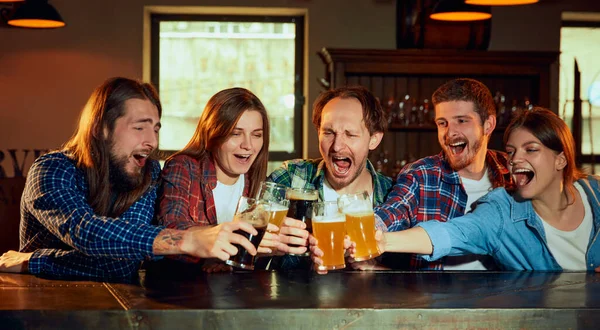 一群年轻人 男人和女人在酒吧看比赛 喝啤酒 球迷们在感情上鼓舞着运动队 庆祝胜利的比赛 锦标赛 比赛翻译 — 图库照片