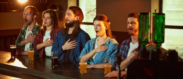 一群年轻人 男人和女人聚集在酒吧看体育比赛的翻译 自豪地唱着队歌 锦标赛 比赛翻译 喝啤酒 — 图库照片