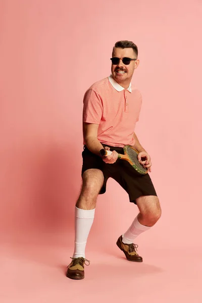英俊迷人的男子的肖像 穿着时髦的衣服摆姿势 在粉红的工作室背景上弹奏网球拍 像吉他一样 运动的概念 复古风格 生活方式 — 图库照片