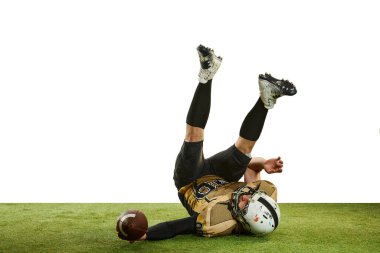 Catching ball and falling. Man, professional american football player in motion over white studio background with green grass flooring. Concept of sport, movement, achievements, competition, hobby