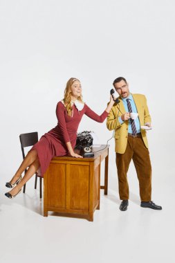 Cheerful woman, personal assistant holding phone handset for businessman drinking coffee. Secretary help. Working routine. Business, professional relationship, communication, team, occupation concept