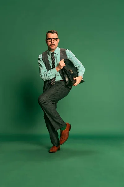 英俊男子的画像 身着古典西装的商人 身披公文包 在绿色工作室的背景上跳舞 面部表情 时尚的概念 — 图库照片