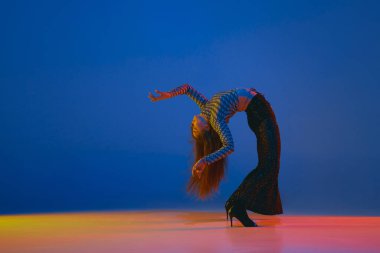 Flexibility. Young girl dancing heels dance in stylish clothes over blue background in neon light. Concept of dance lifestyle, modern style, contemporary, youth culture, self-expression