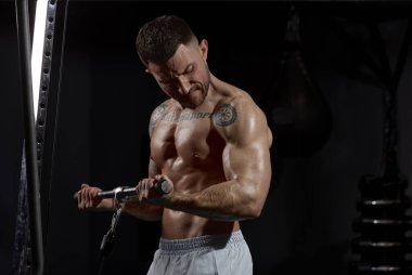 Strong hands. Portrait of young muscular man training shirtless in gym indoors. Hand exercises. Weight-lifting. Concept of health, sportive lifestyle, fitness, body care, diet, strength