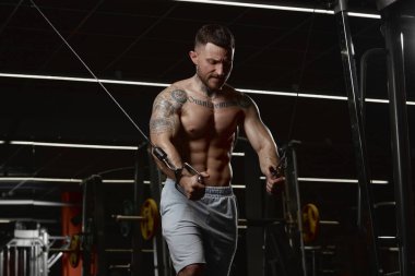 Daily workout session. Muscular man training shirtless in gym indoors. Doing lat pull down exercises. Relief, body shape. Concept of health, sportive lifestyle, fitness, body care, diet, strength