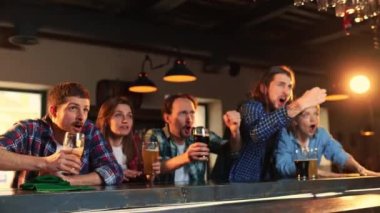 Group of young people, friends, emotionally watching match at pub. Fans cheering up favourite sport team. Winning game. Competition, championship, match translation. Emotions. Goal