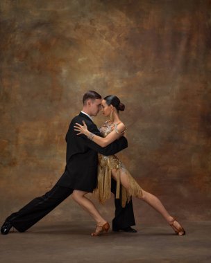 Passionate couple dancing. Man and woman, professional dancers performing ballroom dance over dark vintage background. Theatrical performance. Concept of hobby, lifestyle, action, motion, attraction