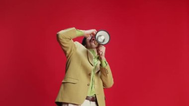 Emotional man, businessman in vintage suit and glasses shouting in megaphone with delightful expression over red background. Win. Concept of emotions, business, occupation, facial expression, fashion