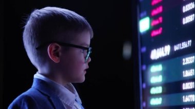 Impressed. Little boy, future businessman looking at computer screen showing financial analytics. Monitor reflection at glasses. Concept of modern technologies, IT, trading, business, finances.