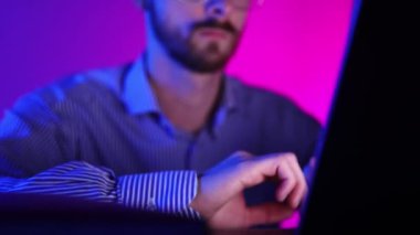 Businessman, freelancer, programmer working on laptop over gradient blue purple background in neon light. Working online. Concept of modern technologies, IT, trading, business, finances.