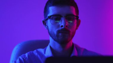 Coding. Businessman, programmer working on new online project, writing website, working on laptop online on gradient purple background in neon light. Modern technologies, IT, business, finances.