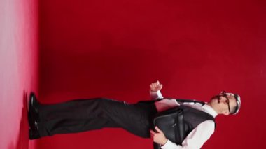 Handsome businessman in official classic suit posing over red studio background. Catching coke on the way, refreshment. Concept of emotions, business, occupation, facial expression, fashion