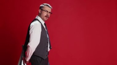 Burning deadlines. Emotional businessman in official classic suit posing, shouting in megaphone over red studio background. Concept of emotions, business, occupation, facial expression, fashion