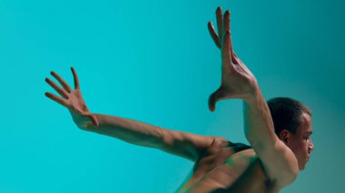 Contemporary dance style. Young artistic man dancing contemp, experimental dance over blue, cyan studio background. Expressive movements. Concept of art, body aesthetics, motion, action, inspiration.