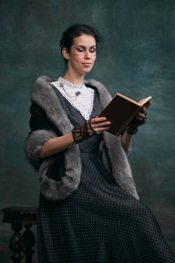 Reading book, story lover. Beautiful woman in image of Anna Karenina in retro clothes over vintage dark green background. Concept of literature character, history, retro style, comparison of eras