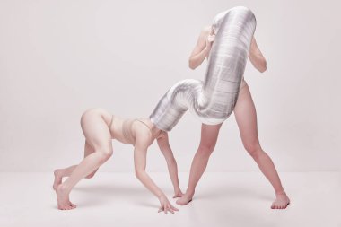 Domination. Creative photography with two young girls posing in nude underwear over beige studio background. Concept of cringe, queer, art photography, weird people, creativity