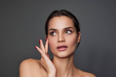 Cosmetological face treatment. Beautiful young girl with smooth well-kept skin over grey studio background. Concept of natural beauty, plastic surgery, cosmetology, cosmetics, skin care