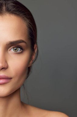 Half-face portraits. Beautiful young girl with smooth well-kept skin, nude makeup over grey studio background. Concept of natural beauty, skin care, cosmetology, cosmetics, health, fashion