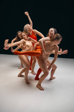 Extraordinary dance. Group of young flexible girls in bodysuits performing contemp over black background. Feelings and inner emotions. Concept of art, movement, youth, fashion, lifestyle, inspiration
