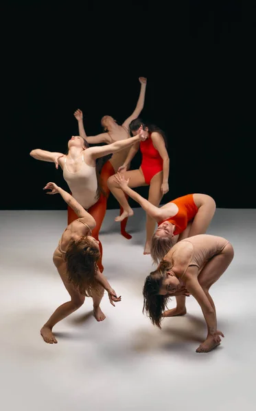 Flow of feelings. Young girls in bodysuits, contemporary, experimental dancers over black background. Concept of art of movement, youth, fashion, artistic lifestyle, flexibility, inspiration