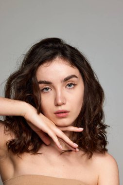 Naturality. Portrait of young beautiful brunette girl with green eyes, healthy well-kept skin over grey studio background. Concept of natural beauty, skincare, cosmetology, plastic surgery, health