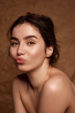 Tenderness. Beautiful young brunette girl with smooth well-kept healthy skin posing over brown studio background. Concept of natural beauty, skincare, cosmetology, plastic surgery, health