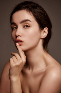 Perfect skin and natural make-up. Portrait of young beautiful girl with brown hair posing over dark grey studio background. Concept of natural beauty, skincare, cosmetology, cosmetics, health