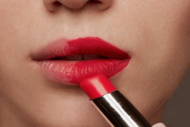 Close-up image of female lips. Female young model applying matte pink, red lipstick, lipgloss. Make-up artist. Concept of natural beauty, skincare, cosmetology, cosmetics, health