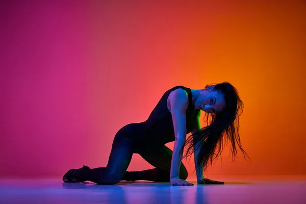 ネオンの光の中でピンクオレンジのグラデーションを舞台上でパフォーマンスする才能ある女性ダンサーのダイナミックなスタジオショット コンテンポラリーダンススタイル アート 創造的なライフスタイルの概念 — ストック写真