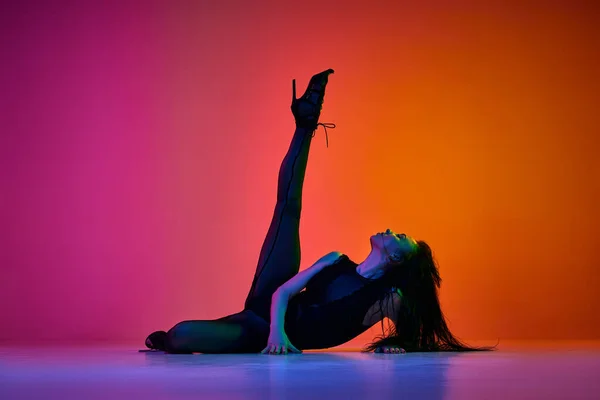 情熱と女性らしさ ネオンの光の中でグラデーションピンクオレンジ色のスタジオの背景に現代的なダンススタイルを行う若い女性ダンサー コンテンポラリーダンスのスタイル アート 創造性の概念 — ストック写真