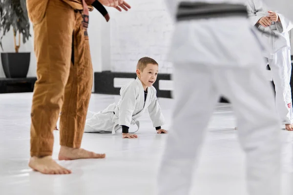Little active boy, child in white kimono attending martial arts school, learning judo, jiu-jitsu fight style. Sportive lifestyle. Concept of martial arts, combat sport, sport education, childhood,