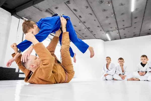 プロの柔道 柔術コーチのトレーニングの種類 男の子 演習を示す 屋内で学ぶ子供たち 武道の概念 戦闘スポーツ スポーツ教育 子供時代 — ストック写真