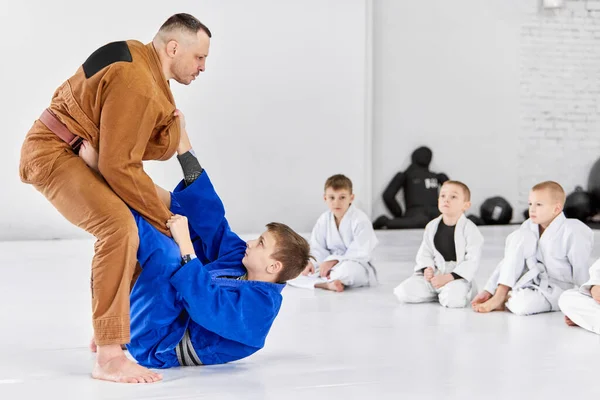 Teacher, professional judo, jiu jitsu coach training kinds, boys, showing exercises. Attention, strength, power. Concept of martial arts, combat sport and sport education, childhood, hobby