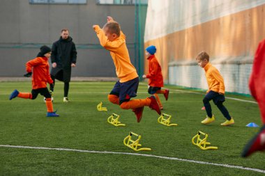 Boys, children, football players doing exercises, warming up before training session with coach on sports field outdoors. Concept of sport, childhood, active lifestyle, hobby, sport club