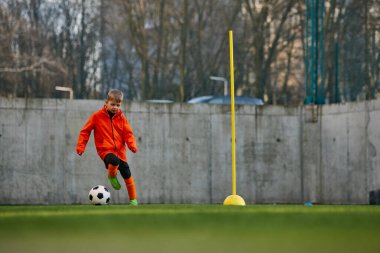Coordinated movements. Little boy, child, football player in uniform training outdoor at sports stadium. Dribbling ball. Concept of sport, childhood, active lifestyle, hobby, sport club